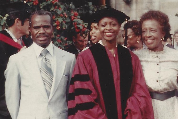 A women wearing a cap and gown poses with her parents.